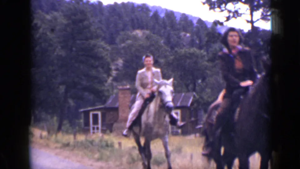 A closer 1939 Colorado frame shows riders on horseback near a roadside building and wooded hillside.