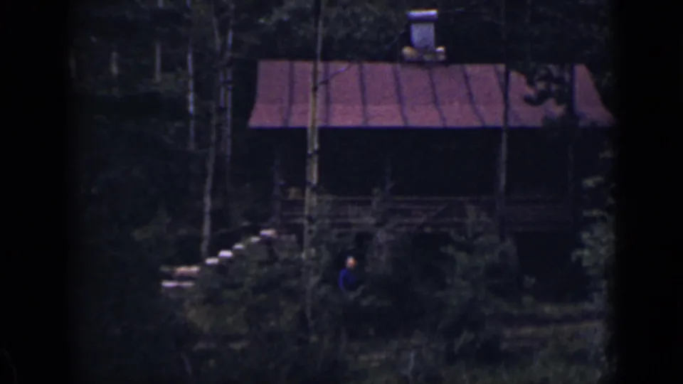 1939 Colorado 8mm frame showing a rustic cabin in dense trees, with a small person visible near the front.
