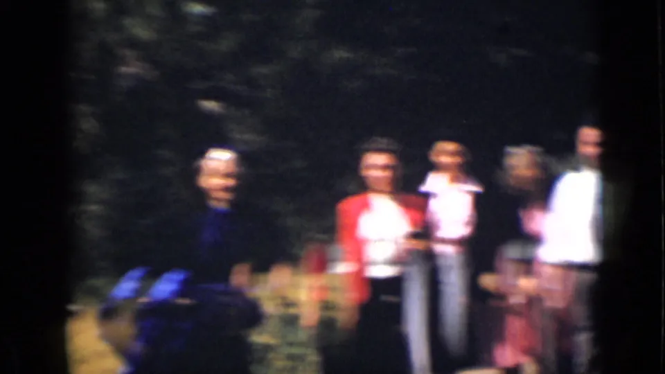 A softly focused 1939 Colorado frame shows a small group of adults outdoors near trees and dry grass.