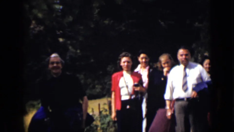 Adults gathered near a shaded Colorado garden path, some facing the camera as the group moves forward.