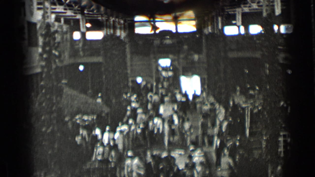 Crowd moving through a large indoor hall with high windows and structural supports.