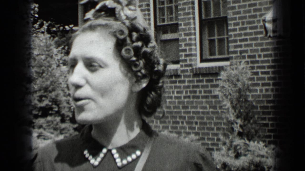 Woman in profile speaks outdoors beside a brick building.