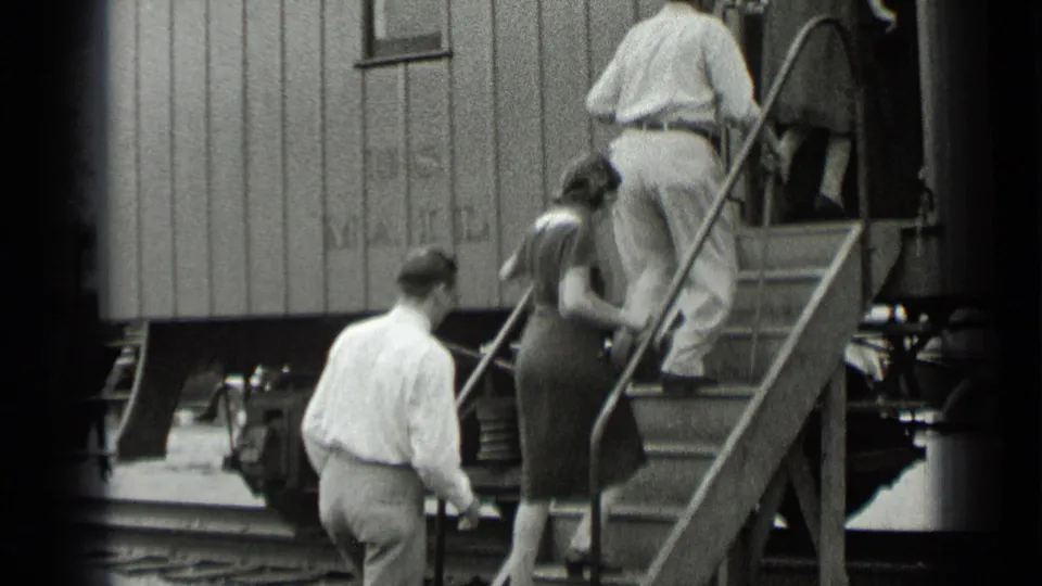 1939 New York frame showing visitors boarding a rail car by metal steps near the steam locomotive display.