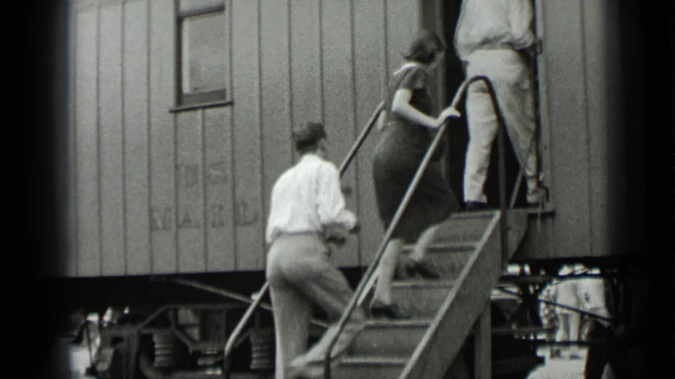 Passengers in late-1930s clothing ascend steps into an open U.S. Mail railcar doorway in New York.