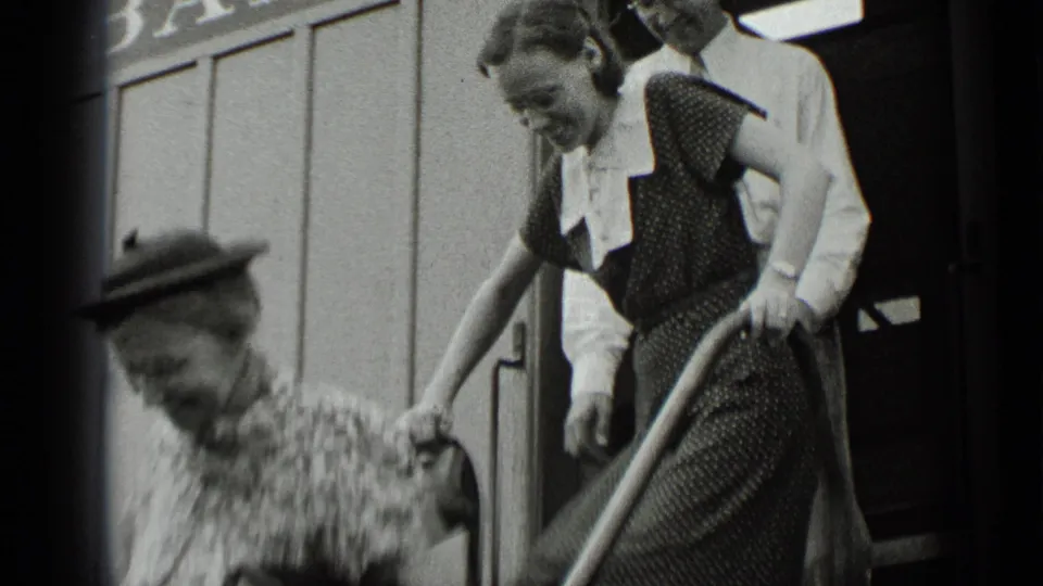 A younger woman in a dark dress and white collar steps down the ride stairs, with a man visible close behind her.