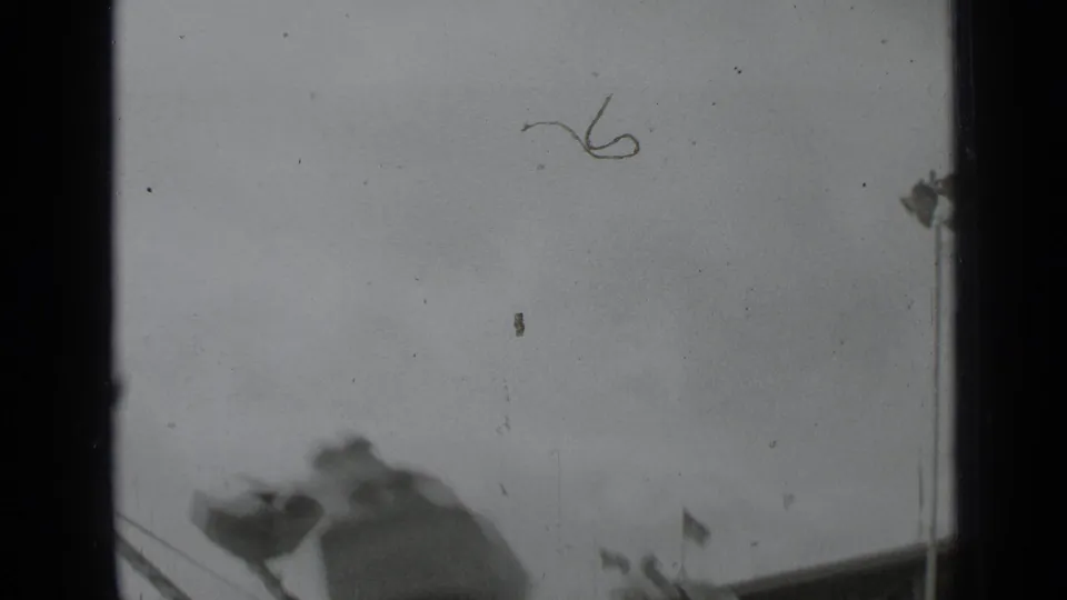 1939 New York fair footage with a blurred amusement structure, small flags, and pronounced 8mm film edge marks.