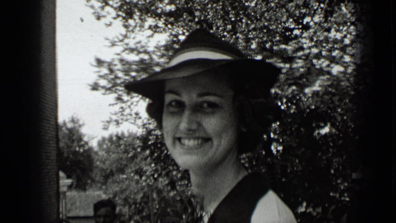 1939 New York home-movie close-up of a smiling woman in a wide-brimmed hat, with trees and a path behind her.