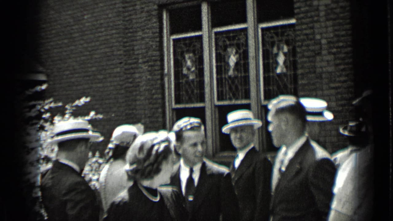 Well-dressed people gather outside a brick building with tall stained-glass windows.