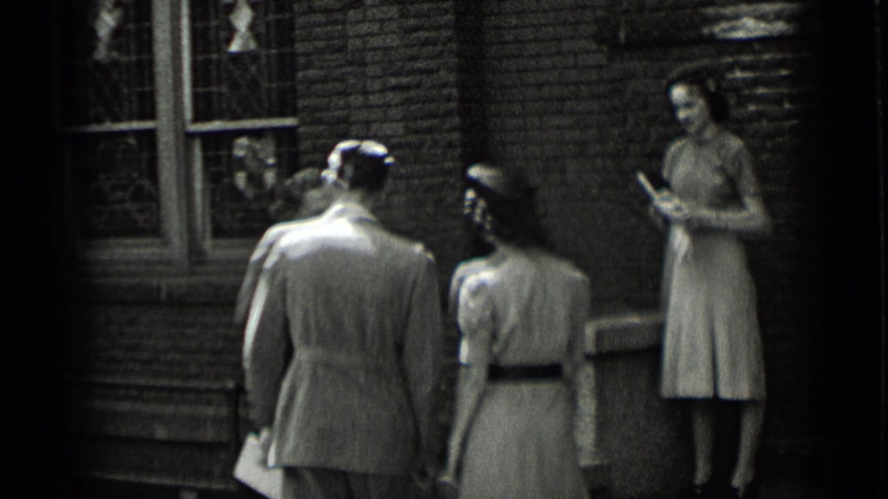 Adults in period clothing stand and turn near stained-glass windows on a brick exterior, with one woman holding a small book or folded item.