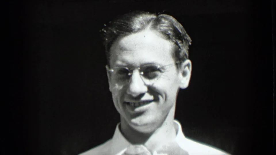 1939 New York home-movie close-up with the man in glasses smiling, his white shirt bright against a dark, indistinct background.