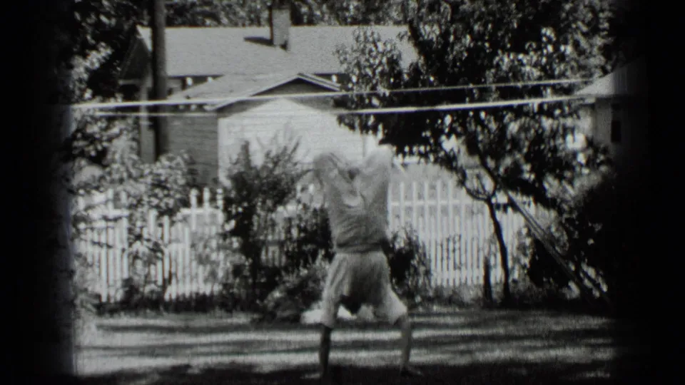 Young man holds a handstand on the grass in 1939 New York home-movie footage, framed by a fence and trees.