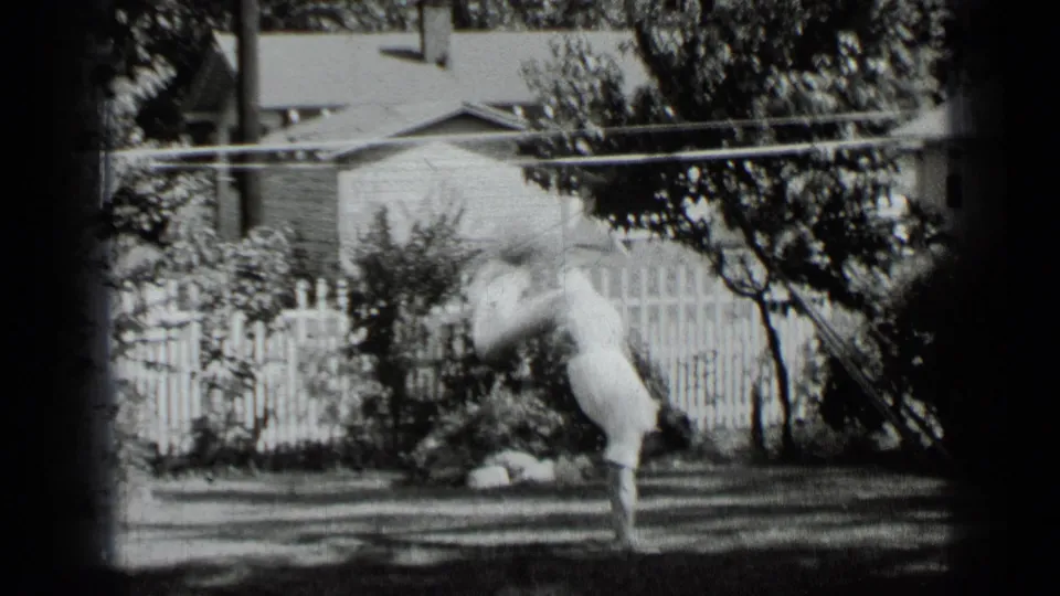 Young man lowers from a backyard handstand in grainy black-and-white 8mm footage from New York in 1939.