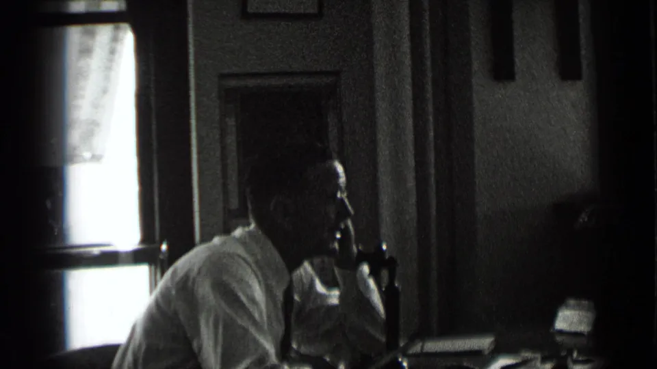 The 1939 New York home movie shows the man leaning forward in profile as he speaks into a desk telephone in a dark interior.