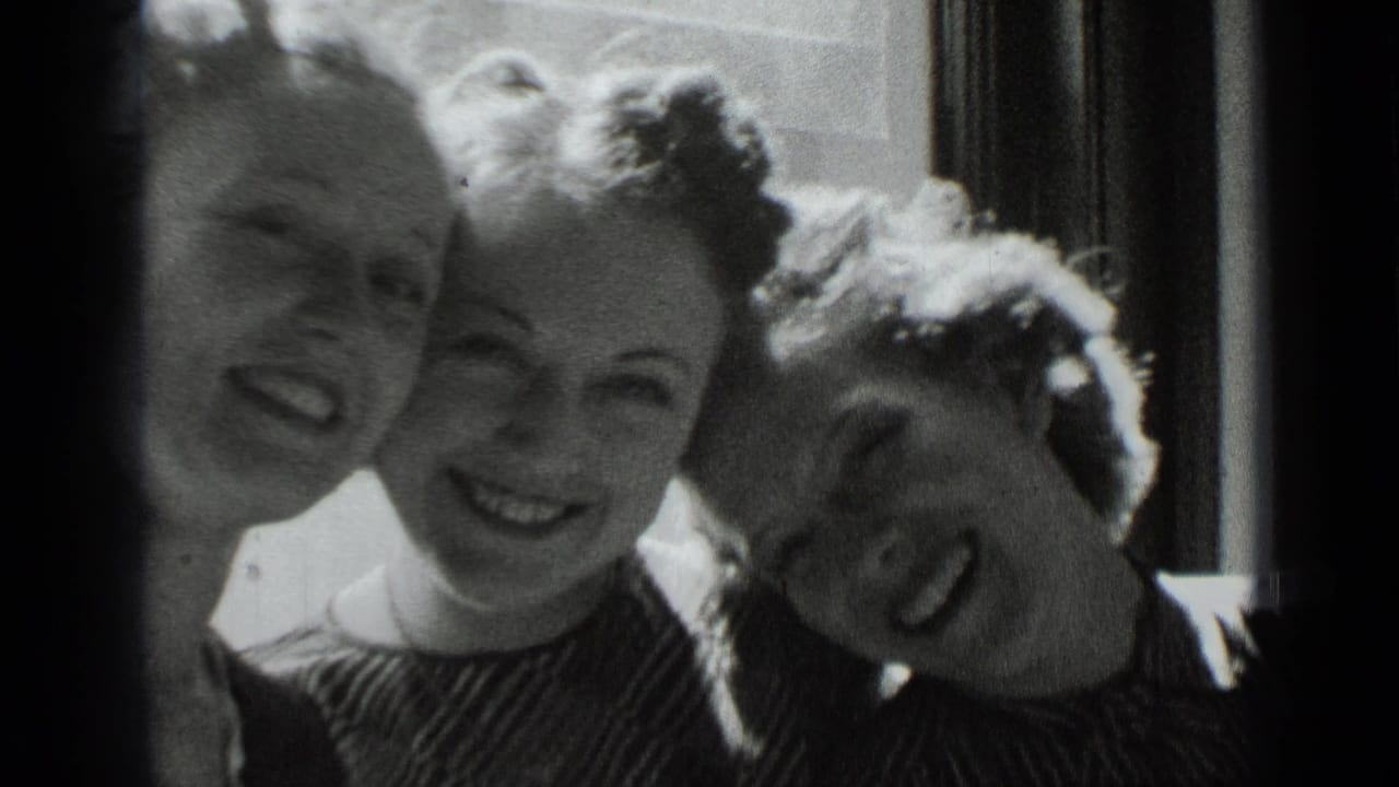 Three young women smile close together beside a bright window.