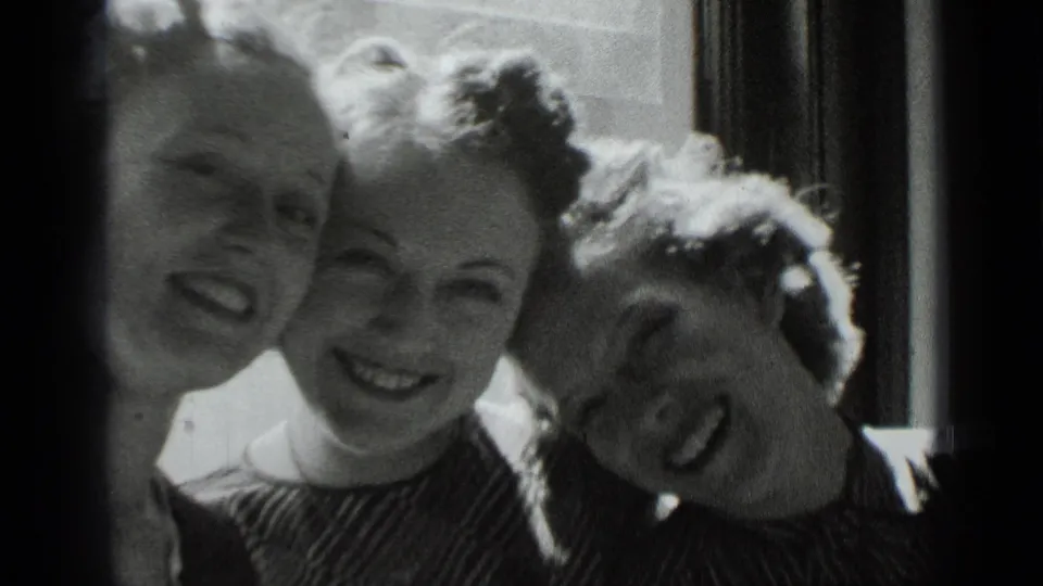 Three young women in 1939 New York home-movie footage smile close to the camera beside a bright interior window.