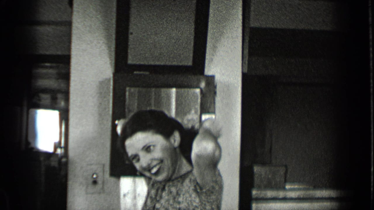 Woman smiling toward the camera beside a desk and dark office doorway.