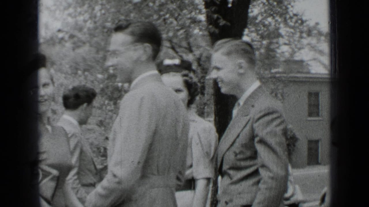 Young adults in dress clothes stand together outdoors, with trees and a building behind them.