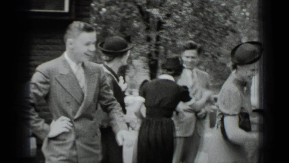 A young man in a suit stands with women wearing hats and dresses in a candid 1939 New York outdoor social scene.