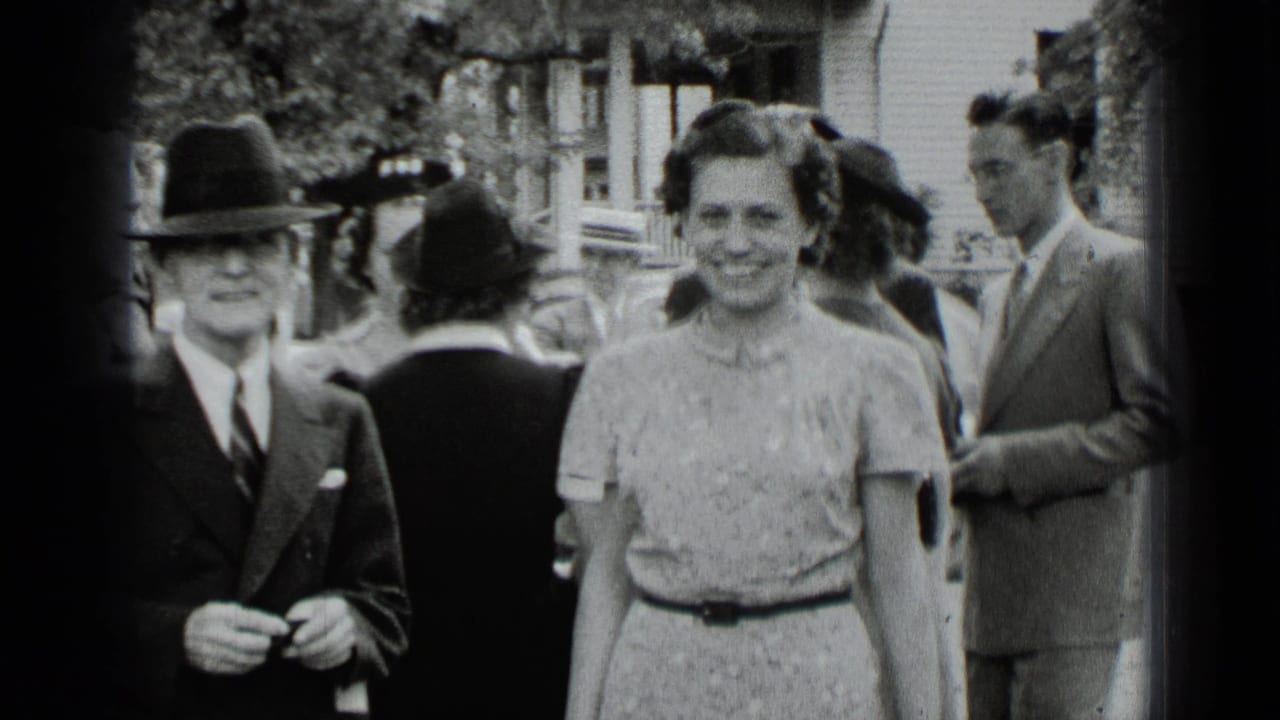 Adults in formal dress stand outdoors, including a man in a fedora and a smiling woman.