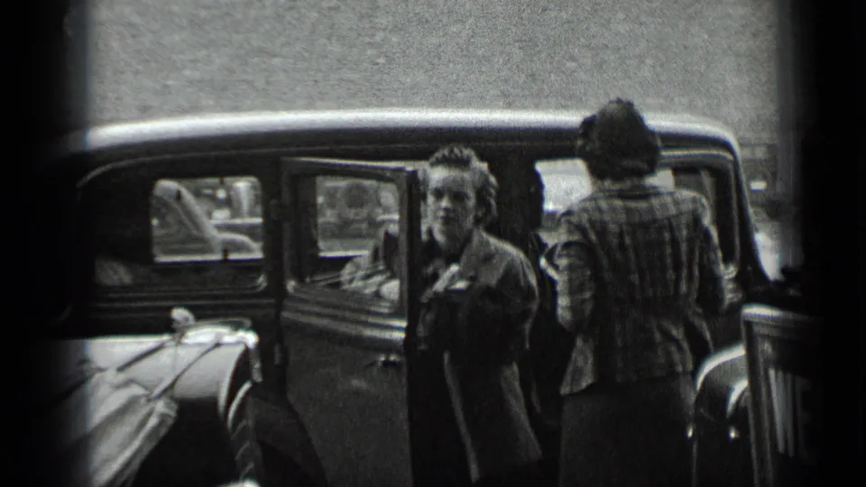 Two adult women stand near a parked car on a New York street in 1939 home-movie footage.
