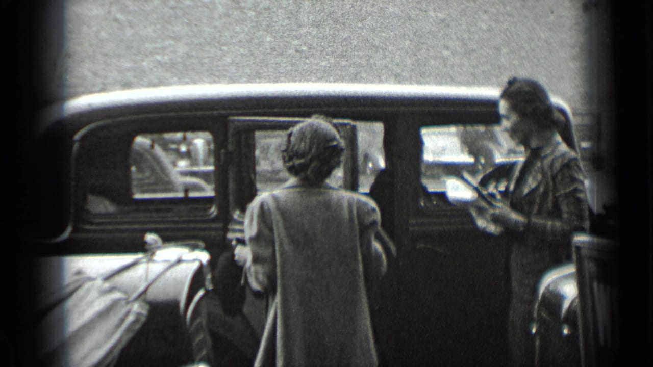 A woman appears to handle the door of a parked car while another woman stands at the curb in 1939 New York footage.