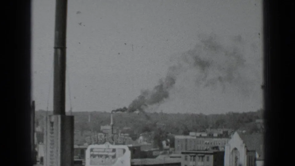 The final 1939 New York view holds on rooftops, a pale church-like facade, and chimney smoke drifting above the city.