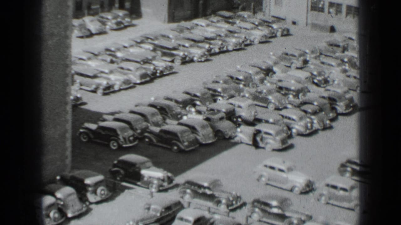 Crowded parking yard with a light-colored car moving out from a row.