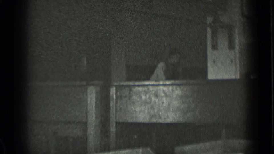 Dark 8mm frame showing an indistinct architectural surface or rooftop detail, likely from the same home-movie sequence.