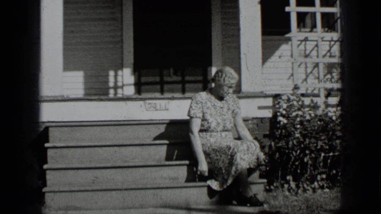 Woman seated on front steps of a house, looking downward.