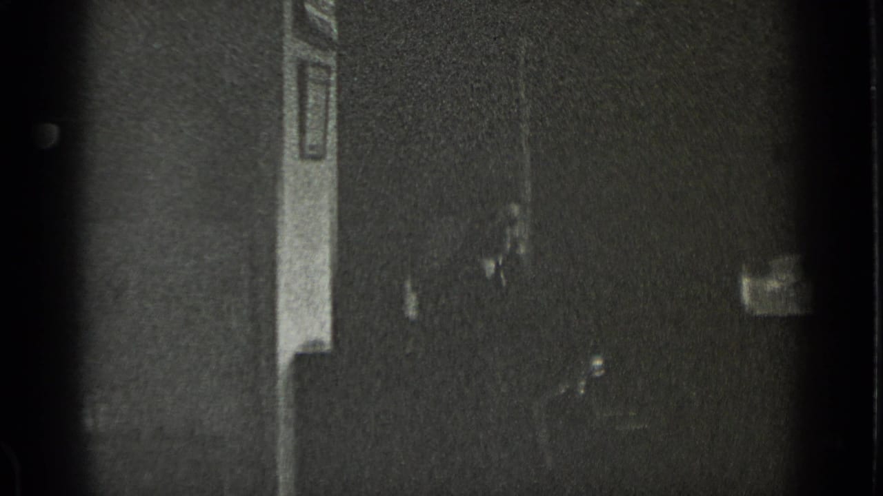 Dim room with window light and a partially visible figure at the right edge.