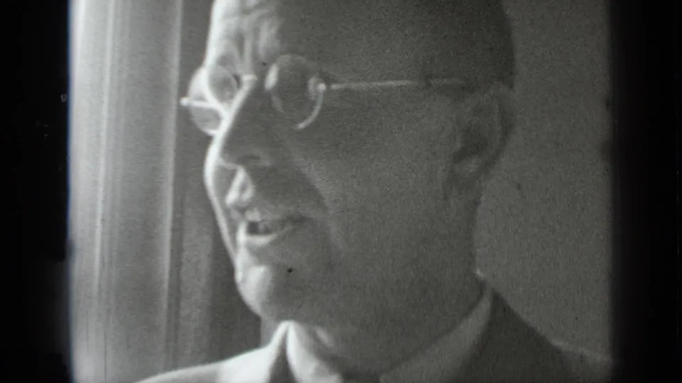 In supplied 1939 New York home-movie footage, an older man in round glasses speaks in profile in a softly lit interior.