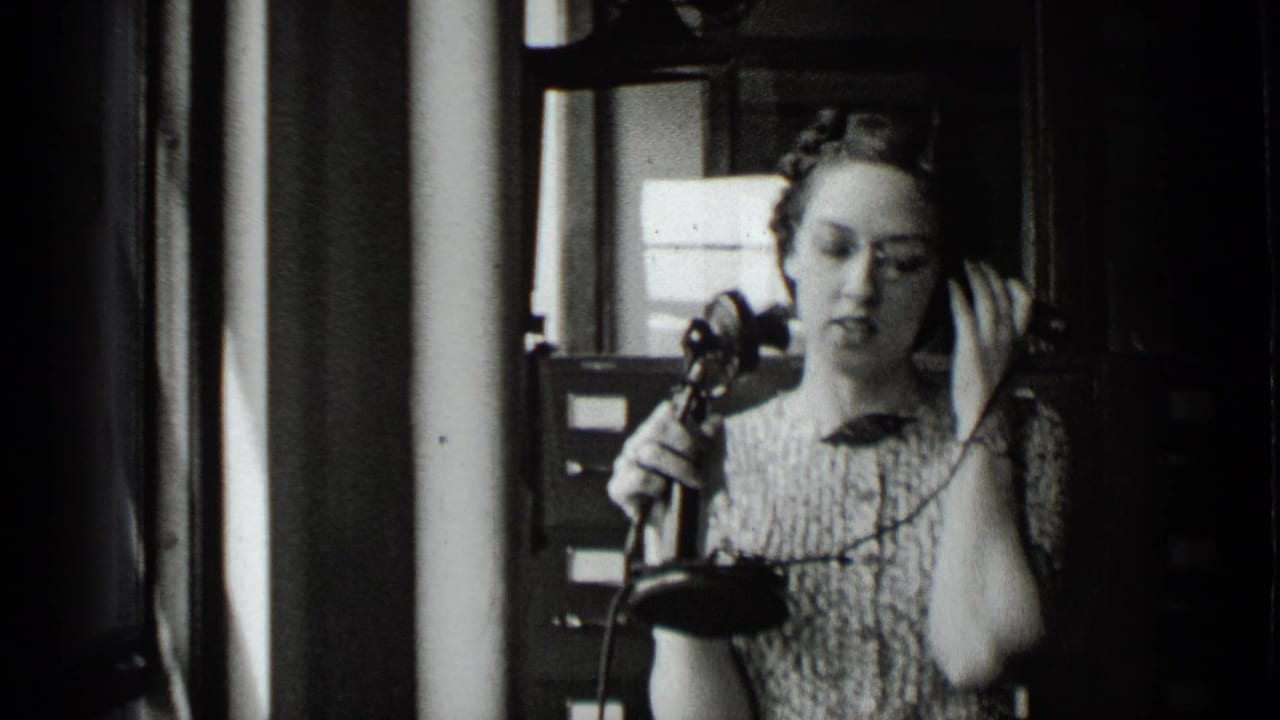 Woman listening on a vintage telephone with her hand raised to her ear.
