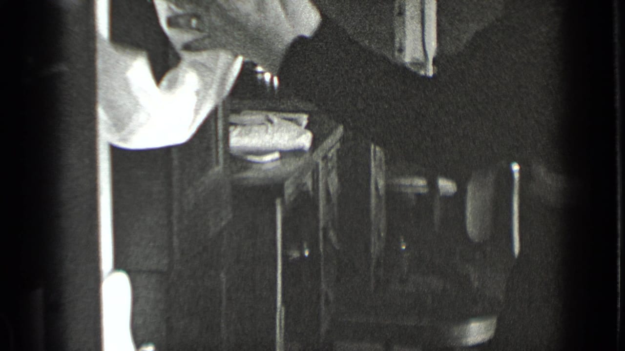 Woman leans at a sink with a white towel visible in a small work area.