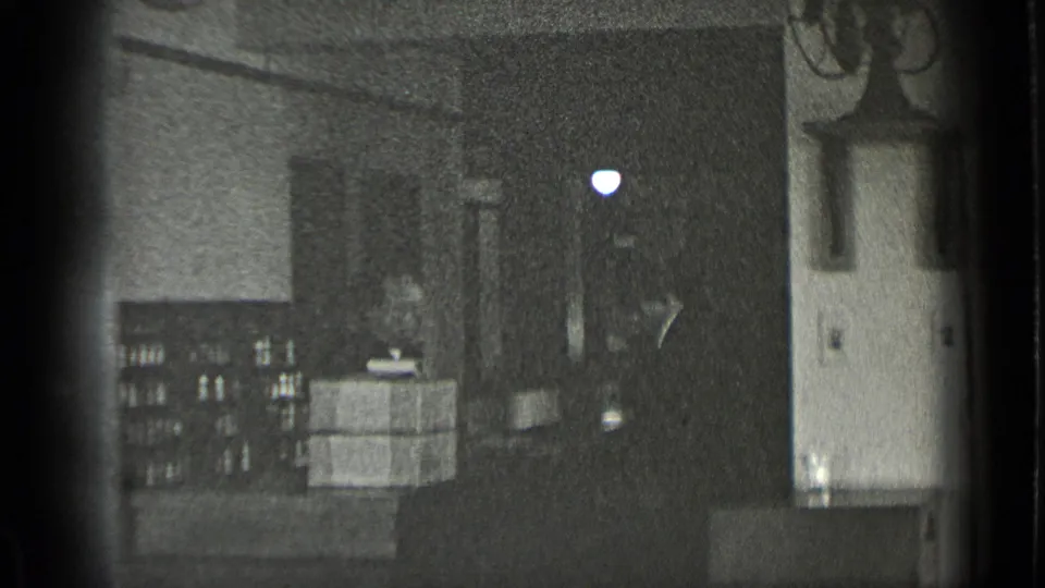 A wider view of the dim workroom shows stacked boxes, shelving, cabinets, and sink fixtures in the 1939 New York clip.
