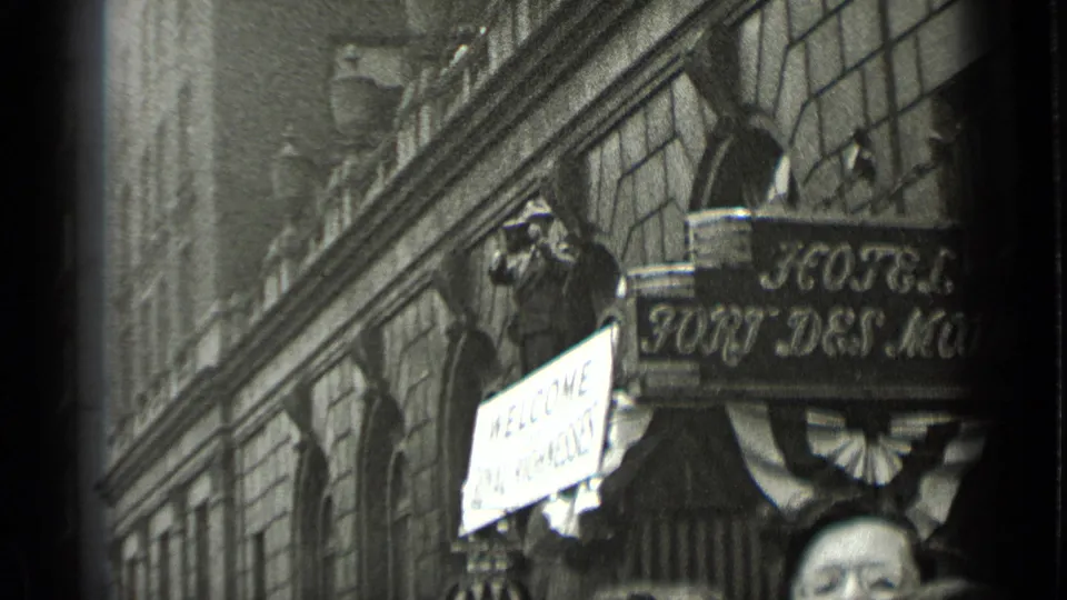 1939 New York hotel exterior with sign lettering, a welcome placard, decorative bunting, and a spectator taking a photograph.