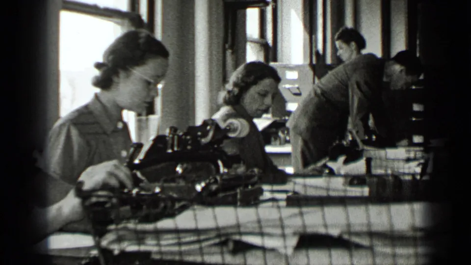 1939 New York office scene with women using manual typewriters while a suited man works near filing cabinets and windows.