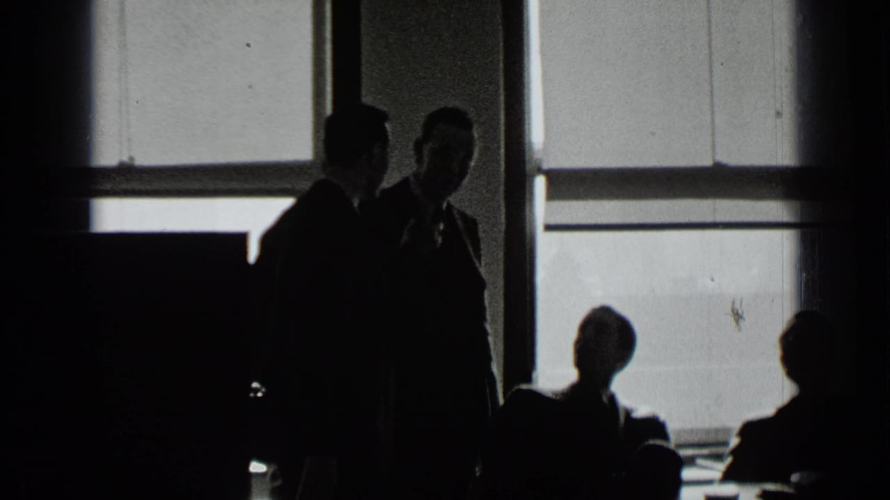 Two standing men face each other near seated silhouettes and bright windows.