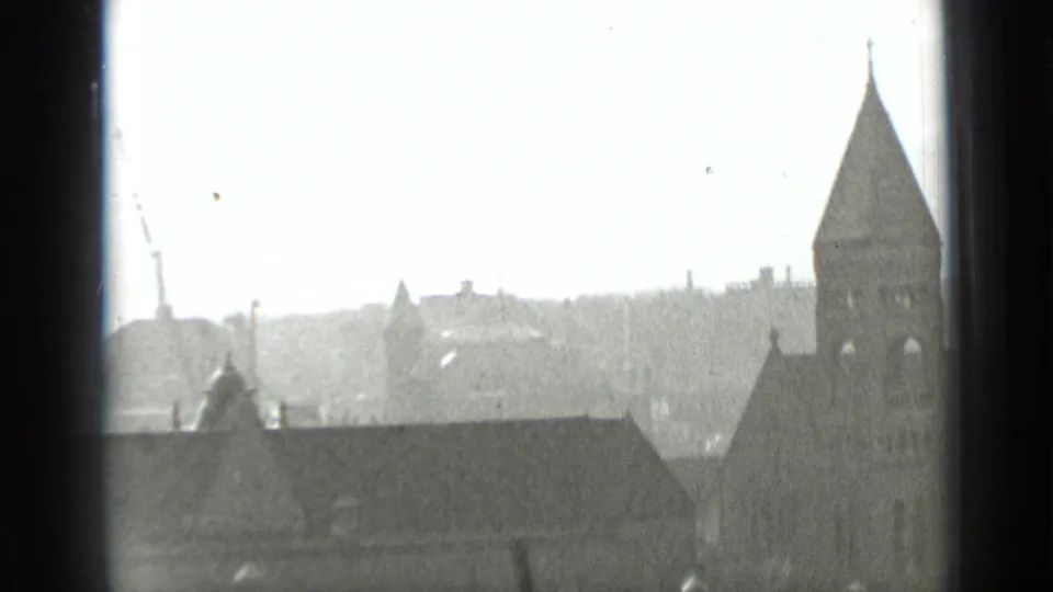 1939 New York view from a high window showing hazy rooftops and a prominent tower or spire beyond the glass.