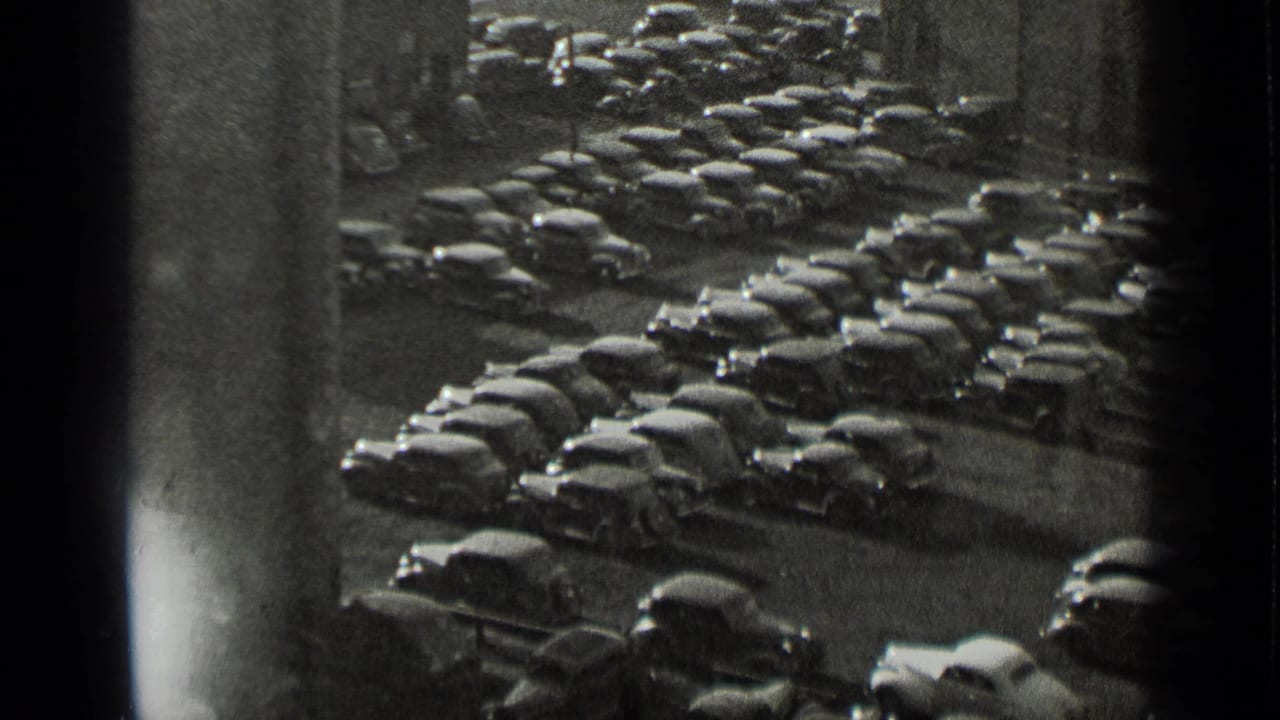 1939 New York home-movie frame showing a high-angle view over a densely packed lot of parked automobiles.