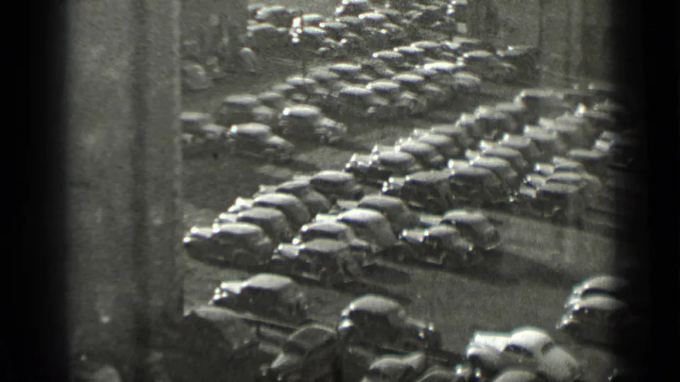 High-angle 1939 New York frame with rows of vintage automobiles packed closely between city structures.