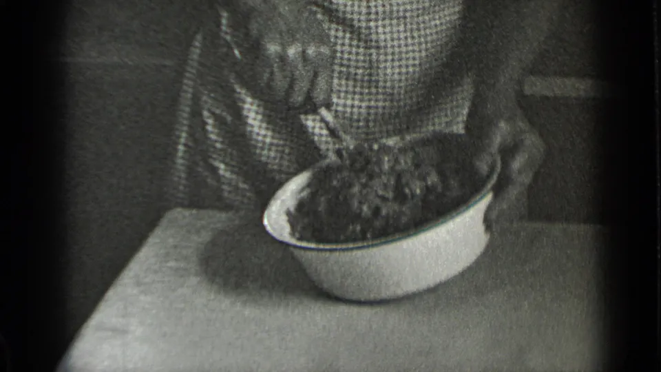 A close home-kitchen view shows the bowl and utensil as the woman continues mashing or mixing food.