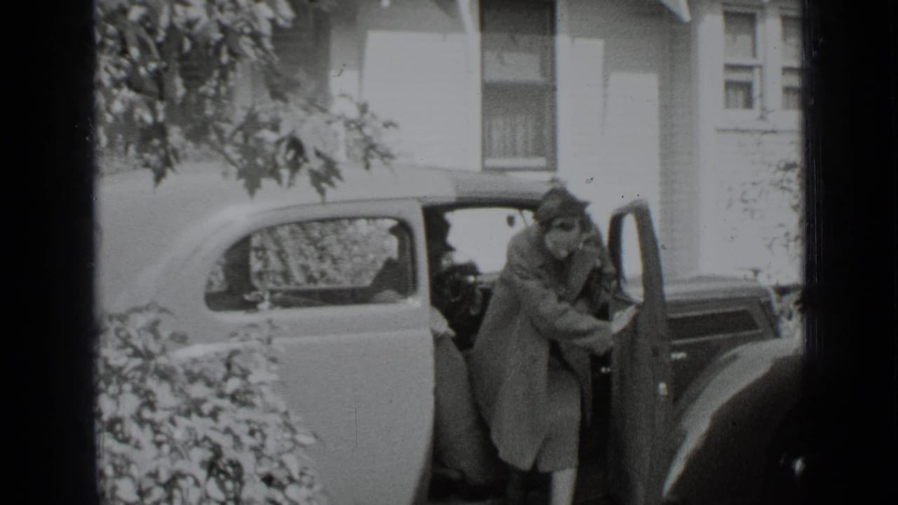 Woman stepping out of a vintage car beside a house.