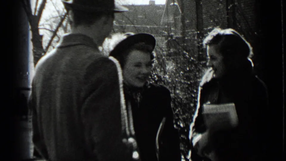 In 1939 New York home-movie footage, adults in heavy coats and hats converse on a bright winter sidewalk.