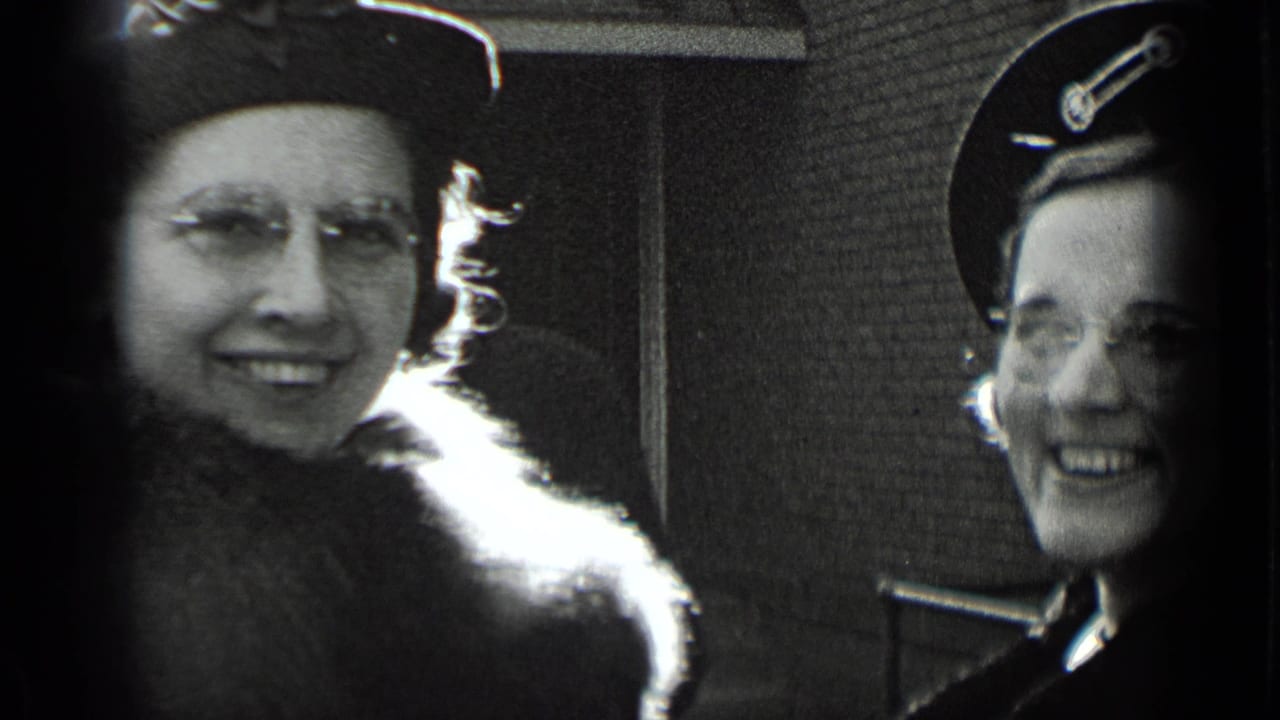 Two women smile in close-up, one partly framed by a dark film edge.