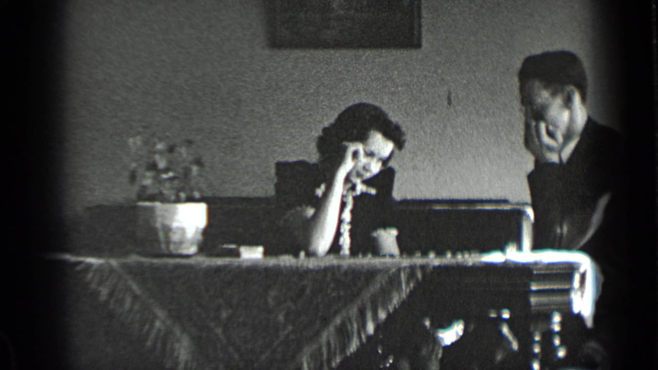 Young woman and man sit at a dining table with a potted plant and checkers board.
