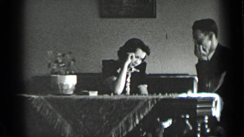 In a 1939 New York home-movie frame, a young couple sits at a dining-room table during a checkers game.