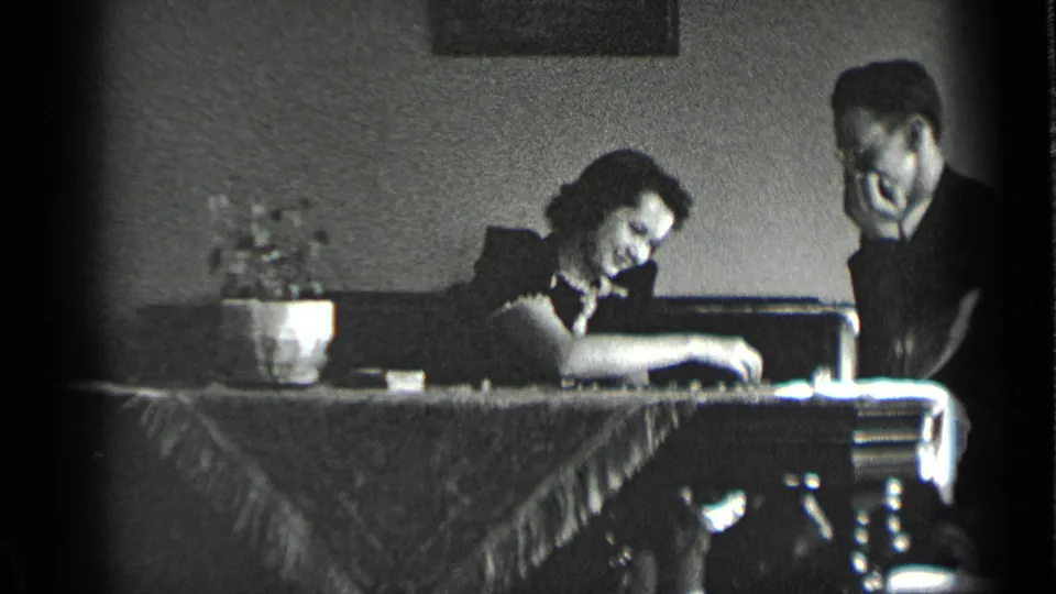 The woman reaches or studies the board while the man sits nearby in this 1939 New York domestic scene.