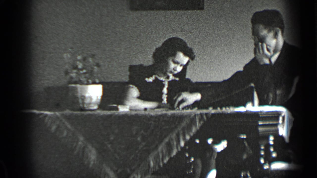 Woman leans over the table while the man reaches toward the tabletop.