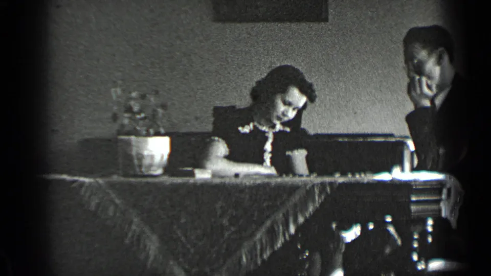 In this dim 1939 New York home interior, the woman remains focused on the table and the man sits beside her in a contemplative pose.