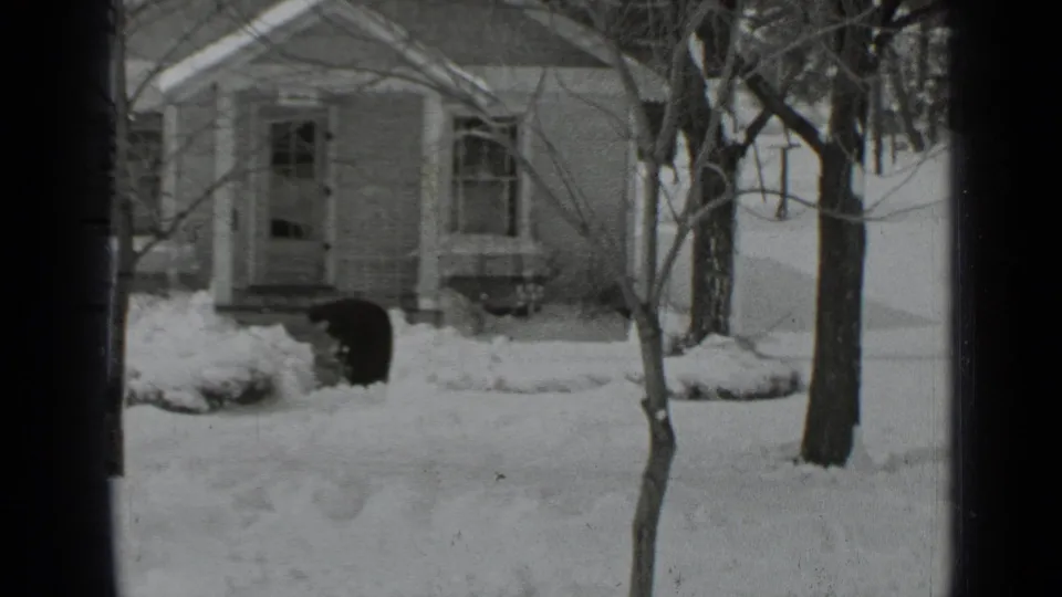1939 New York residential winter view with snow-covered ground, bare trees, a modest house, and dark window framing.